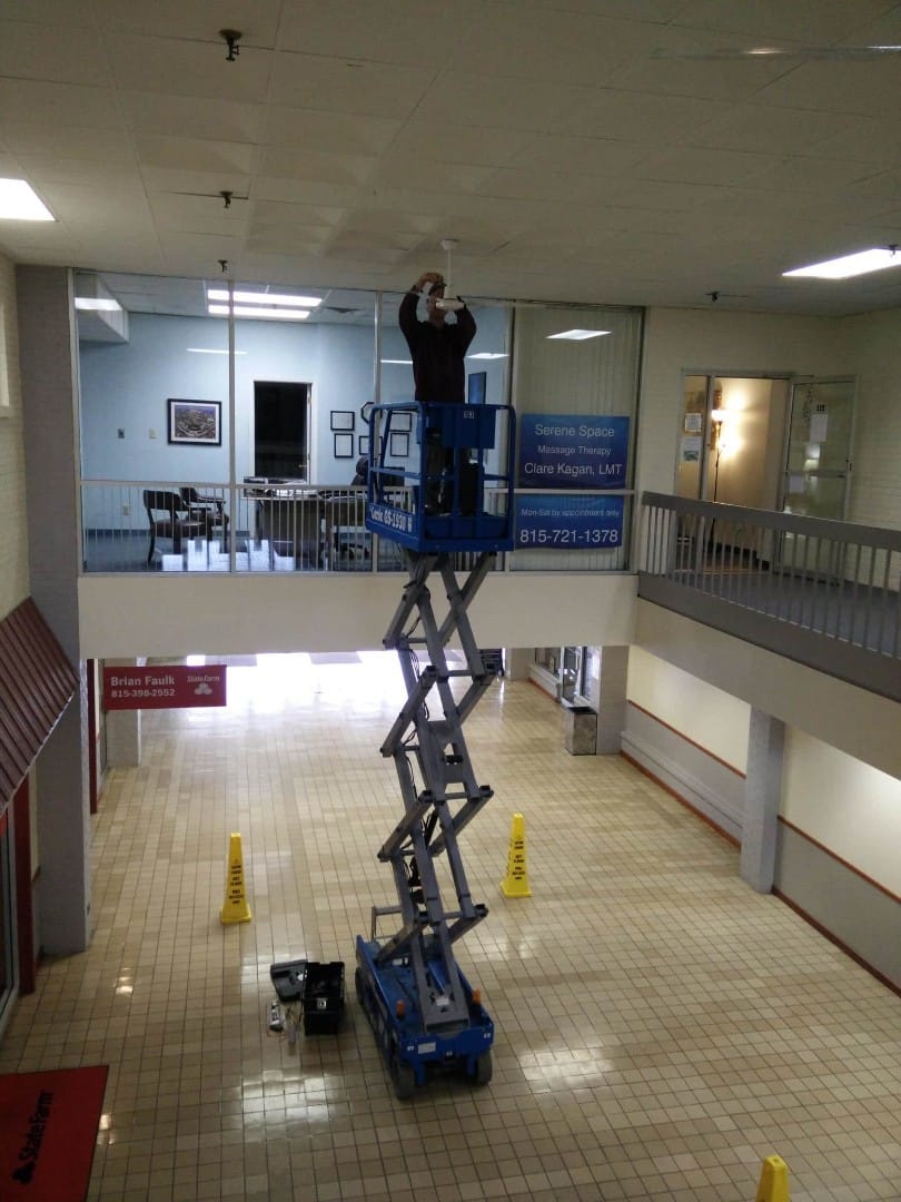 Installing new ceiling fan in shopping center with scissor lift.